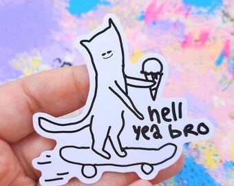May include: A white sticker featuring a cartoon cat riding a skateboard and holding an ice cream cone. The text "hell yea bro" is written below the skateboard in black. The sticker has a black outline.