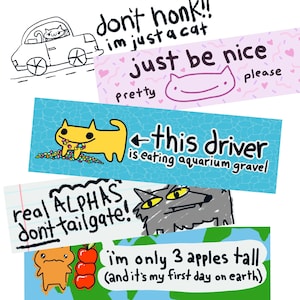 May include: A collection of whimsical bumper stickers with various cartoon illustrations and text. One sticker features a cat in a car with the text "don't honk!! I'm just a cat." Another says "just be nice" with a cat face. Other stickers include "this driver is eating aquarium gravel."
