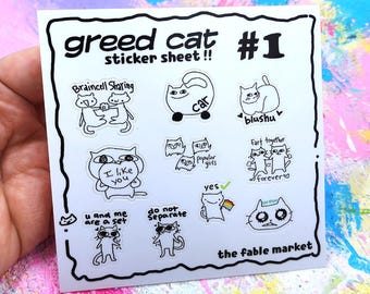 May include: A white sticker sheet with black line art cat illustrations. The text "greed cat sticker sheet !! #1" is at the top. The sheet includes various cat designs with phrases like "I like you" and "do not separate". The words "the fable market" are at the bottom.