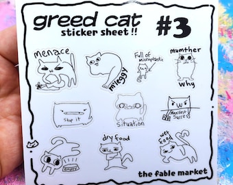 May include: A white sticker sheet with black line art cat illustrations. The sheet includes the text "greed cat sticker sheet !! #3" and various cat drawings with phrases like "menace", "m'leggy", "stop it", and "dry food". The bottom right corner reads "the fable market".