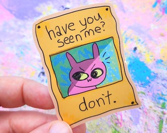 May include: A sticker featuring a cartoon rabbit with an angry expression inside a yellow frame. The frame reads "have you seen me?" and "don't." The rabbit is pink with large yellow eyes and a small "w" on its mouth.