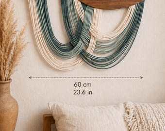 May include: A handmade wall hanging with a wooden top and woven strands in cream and teal. The artwork is 23.6 inches wide and features the text "Handmade with Love". The style is Boho, natural, and timeless.