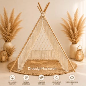 May include: A beige macrame teepee tent with natural wood poles, set on a round jute rug. The tent features a woven design and fringe detailing. The image includes text that reads "DrdesignHazineleri", "100% Cotton Macrame", "Natural Wood Poles", "Handmade with Love", "Easy to Set Up & Portable", and "Indoor & Outdoor Use".