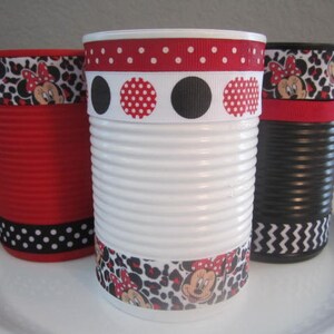 May include: Three decorated tin cans with red, black, and white polka dot and animal print ribbon. The cans are painted white, red, and black.