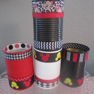May include: Four black and white decorated cans with red, yellow, and black ribbon. The cans are decorated with Mickey Mouse ears, polka dots, and a houndstooth pattern.