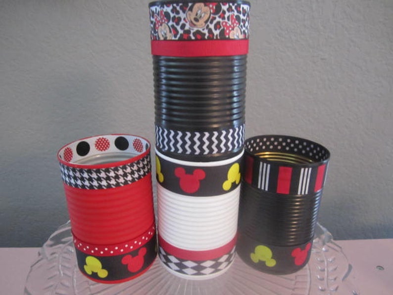 May include: Four black and white decorated cans with red, yellow, and black ribbon. The cans are decorated with Mickey Mouse ears, polka dots, and a houndstooth pattern.