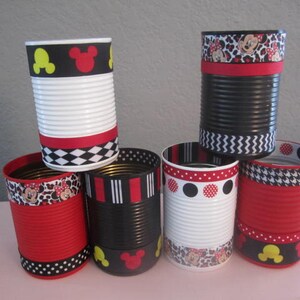 May include: Six decorated metal cans with red, black, and white stripes, polka dots, and Mickey Mouse designs. The cans are used as pencil holders or other small item storage.