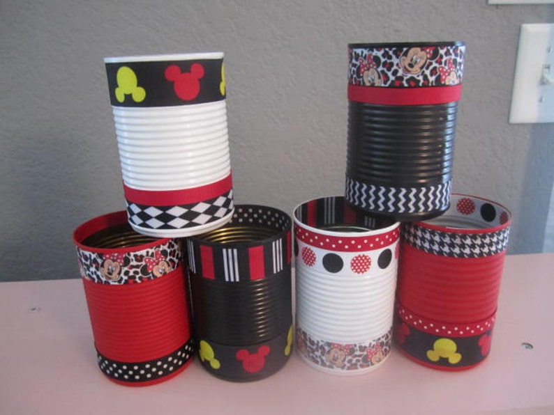 May include: Six decorated metal cans with red, black, and white stripes, polka dots, and Mickey Mouse designs. The cans are used as pencil holders or other small item storage.