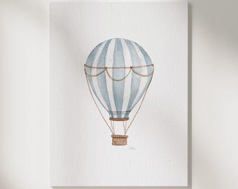 May include: A watercolor illustration of a hot air balloon with vertical light blue and white stripes, featuring brown ropes and a small brown basket. The text Print & Shipping, Hand-Painted by Artist, and ostelaris.art are visible on the page.