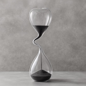 May include: A clear glass hourglass with a distinctive, curved shape. The top section contains black sand, currently flowing into the lower chamber. This decorative hourglass is a stylish timekeeping device.