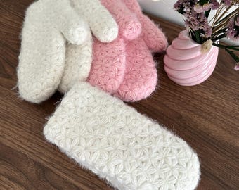 Peut inclure: Une paire de moufles blanches duveteuses, une paire de moufles roses duveteuses et un bandeau blanc duveteux, tous dotés d'un motif de points texturés en forme d'étoile. Les articles sont fabriqués dans une matière douce avec un motif floral en relief.