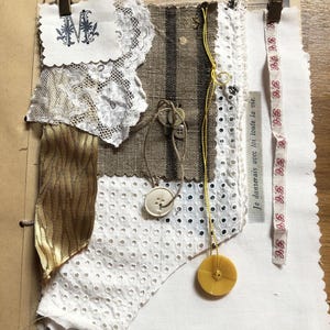 Può includere: Un collage tessile con pizzo bianco con una lettera M ricamata in blu, lino marrone con strisce nere, tessuto bianco occhiellato, un nastro dorato e una striscia di tessuto bianco con testo rosso. Include bottoni e un filo giallo con bottone.