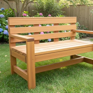 Puede incluir: Banco de jardín de madera con acabado natural. El banco tiene asiento y respaldo de listones, con reposabrazos. Está situado sobre un césped verde, con una valla de madera y exuberante vegetación de fondo, incluyendo hortensias.