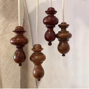 Puede incluir: Cuatro tiradores de luz de madera con un diseño clásico. Los tiradores son de color marrón oscuro, con un acabado liso y pulido. Cada tirador está suspendido por un cordón de color crema. Los tiradores tienen una forma bulbosa con un pequeño pomo redondeado en la parte inferior.