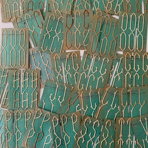 May include: A selection of vintage monogram embroidery cards. Each card displays a different letter in a cream-coloured, stylized font. The cards are teal green with the words "MONOGRAMME à broder" printed on them.