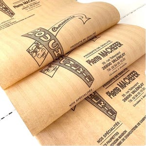 May include: Light brown wrapping paper featuring black printed text and graphics for Pierre Machefer. The design includes the text Boucherie, Charcuterie, Produits de Qualité, and contact details for the shop located in Valençay, France.
