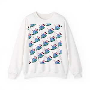 Könnte beinhalten: Weißes Sweatshirt mit einem sich wiederholenden Muster aus blauen, rosa und grünen geometrischen Formen. Das Design umfasst Dreiecke, Kreise und Text auf einem türkisfarbenen Banner. Das Sweatshirt hat lange Ärmel und einen Rundhalsausschnitt.