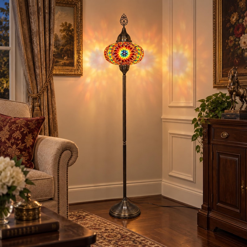 May include: A tall floor lamp featuring a round, multi-colored mosaic glass shade with intricate geometric patterns in red, yellow, blue, and green. The lamp has a slender, dark metal stand and a circular base, emitting a warm, glowing light.