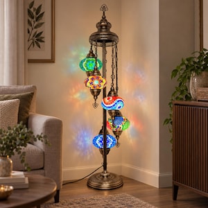 May include: A tall floor lamp with a dark bronze metal stand and five hanging mosaic glass globes in various colors including blue, green, red, and yellow. The globes emit a multi-colored light pattern onto the surrounding walls.