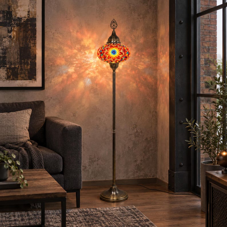May include: A tall floor lamp featuring a vibrant, multi-colored mosaic glass shade with intricate geometric patterns. The lamp has a slender, antique brass-finished metal stand and a circular base, emitting a warm, glowing light.