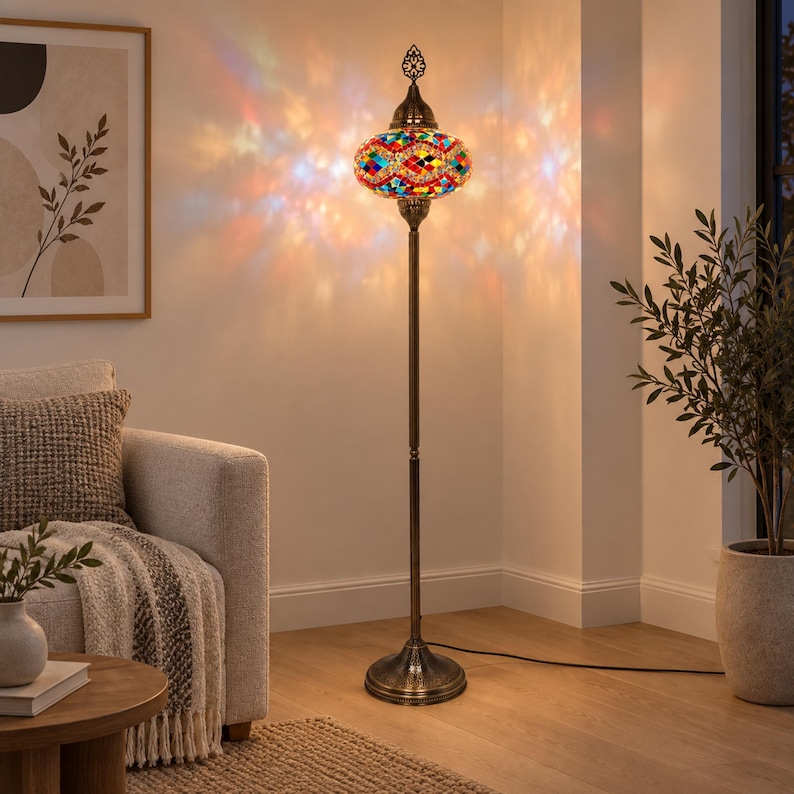 May include: A tall floor lamp featuring a multi-colored mosaic glass shade with a geometric pattern. The lamp has a slender, dark bronze-toned metal stand and a circular base, casting a vibrant, warm, and multi-colored light pattern on the wall.