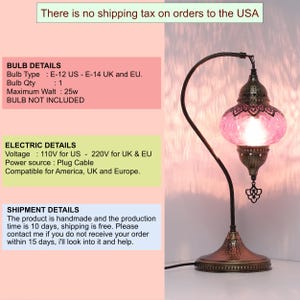 May include: A decorative table lamp with a pink, mosaic-style glass shade. The lamp has a bronze-colored metal base and a curved arm. The lamp is designed for use with an E-12 bulb and is compatible with 110V power in the US.