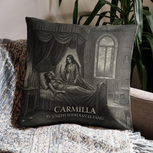 Può includere: Cuscino decorativo in bianco e nero con un'illustrazione dal romanzo "Carmilla" di Joseph Sheridan Le Fanu. L'immagine raffigura due donne in una camera da letto. Il cuscino è posto su una coperta fantasia.