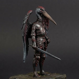 May include: A detailed figurine of a bird-headed knight in full armor, holding a sword. The figure has feathered wings and stands on a stone base. The armor is dark red and metallic, with intricate detailing. The bird's head has a long beak.