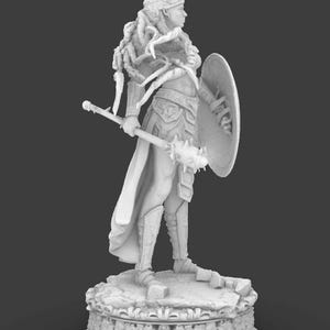 May include: A monochrome figurine of a warrior woman, holding a mace and shield, and wearing armour. The figure stands on a decorative base, with detailed design. The warrior is in a side profile pose, showcasing the intricate details of the figure.