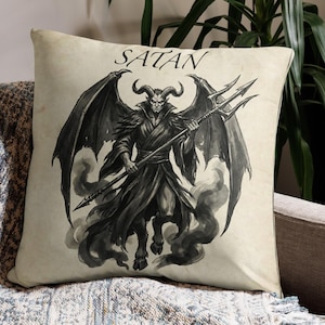 May include: Square throw pillow with a vintage-style illustration of Satan. The black and white image depicts a horned demon with large wings, holding a trident. The word "SATAN" is printed across the top.
