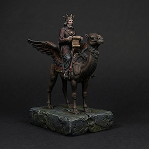 May include: A detailed figurine of a king riding a camel with feathered wings. The king wears a crown and holds a scroll. The camel is brown, and the king's robes are burgundy. The figurine rests on a stone base.