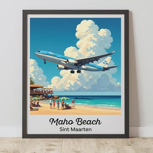 May include: A framed art print of Maho Beach, Sint Maarten. A KLM airplane is descending over the beach with people, umbrellas, and a restaurant. The sky is blue with puffy white clouds.