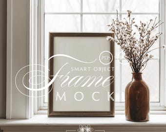 Könnte beinhalten: Ein brauner Holzbilderrahmen mit dem Text "Frame Mock" wird auf einer Fensterbank präsentiert. Rechts vom Rahmen befindet sich eine braune Vase mit weißen Blumen. Der Rahmen ist ein Smart-Object-Mockup.