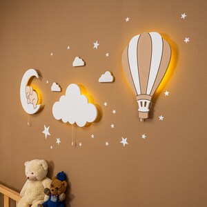 Wooden nursery wall decor set with hot air balloon, glowing cloud and crescent moon night lights for baby room, warm LED Montessori nursery lighting made from plywood, Scandinavian style neutral beige wall decoration for toddler bedroom, handcrafted baby nursery lamp set with stars and clouds, soft ambient lighting for newborn room, modern kids room wall art with illuminated balloon and moon design.