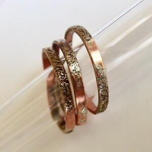 May include: Three stacked rings, one copper and two silver, with a textured finish.