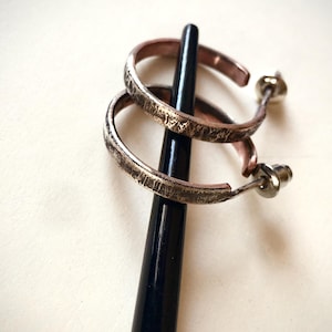 Zwei Herrenohrringe aus der Darck-Kollektion aus massivem Kupfer und Silber.