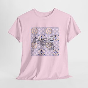 Può includere: T-shirt rosa chiaro con un design geometrico di una mappa della Sicilia, Italia, sovrapposto a un motivo di piastrelle blu, gialle e bianche. La t-shirt ha maniche corte e girocollo.