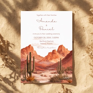 May include: Wedding invitation featuring a watercolor illustration of a desert landscape with cacti and red rock formations. The invitation includes the names "Amanda & Daniel" and wedding details: October 28, 20XX, 3:00 PM, Red Rock Overlook, Sedona, Arizona.