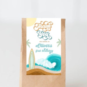 May include: A brown paper bag with a thank you tag. The tag has a blue and white wave design with a surfboard and palm trees. The text on the tag reads "Thank You for coming to Oliver's first birthday."