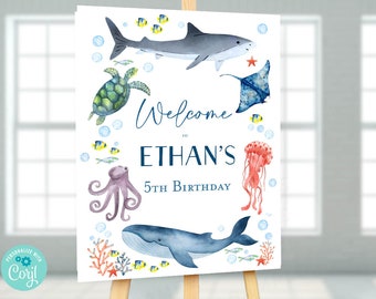 May include: Welcome to Ethan's 5th Birthday party sign featuring a blue whale, a shark, a jellyfish, an octopus, a turtle, and a stingray. The sign is on a white background with blue and yellow bubbles.