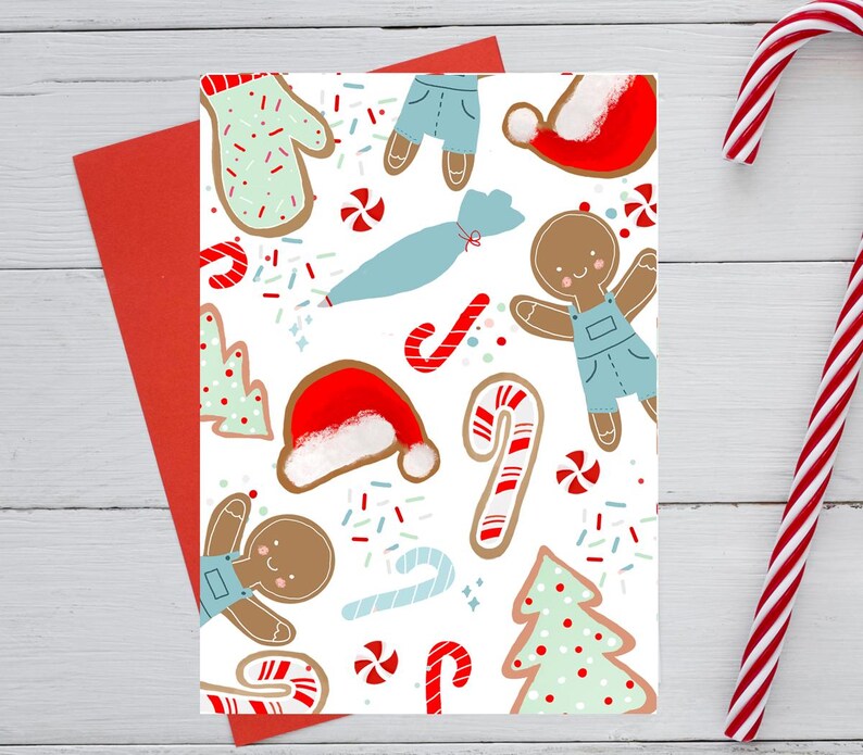 May include: A Christmas-themed greeting card with a festive pattern of gingerbread cookies, candy canes, Santa hats, and sprinkles on a white background. A red envelope is visible behind the card, with a candy cane on the right.