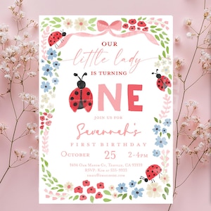 May include: A birthday invitation with a floral and ladybug theme. The invitation reads "Our little lady is turning ONE" and includes the name "Savannah" and the date October 25th.
