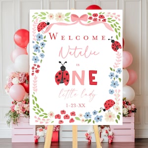 Nyckelpiga första födelsedagsvälkomstskylt vår lilla dam är ett, rosa rosettblommig 1-års födelsedagsdekorationer nyckelpiga flicka baby utskrivbar banner