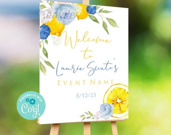 May include: Welcome to Laurie Sveto's EVENT NAME 8/12/23 sign with a lemon and floral design. The sign is white with blue and yellow watercolor flowers and lemons.