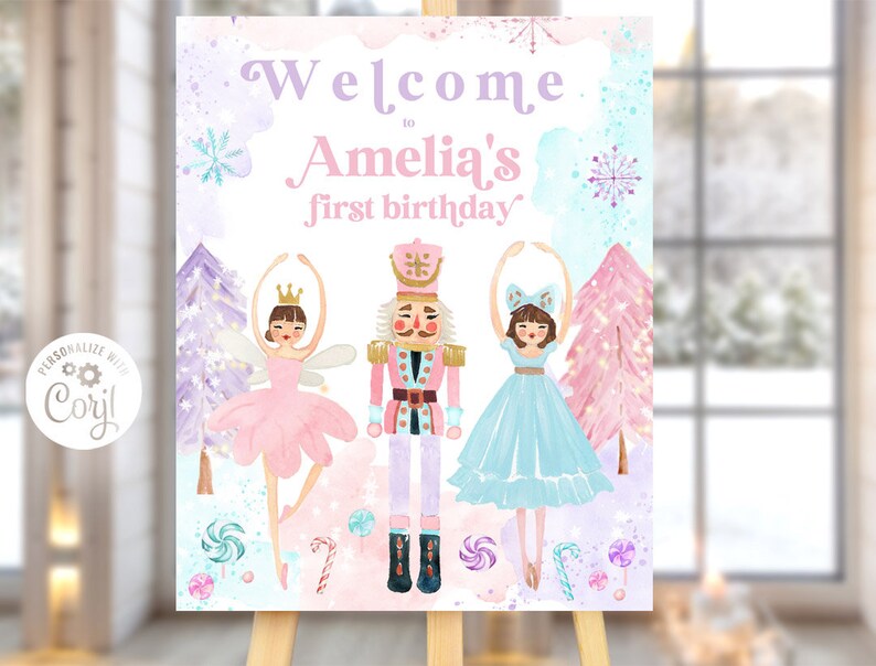 May include: A rectangular sign featuring the text Welcome to Amelia's first birthday. The design includes a central nutcracker figure flanked by two ballerinas, surrounded by watercolor-style pink and purple trees, snowflakes, and candy.