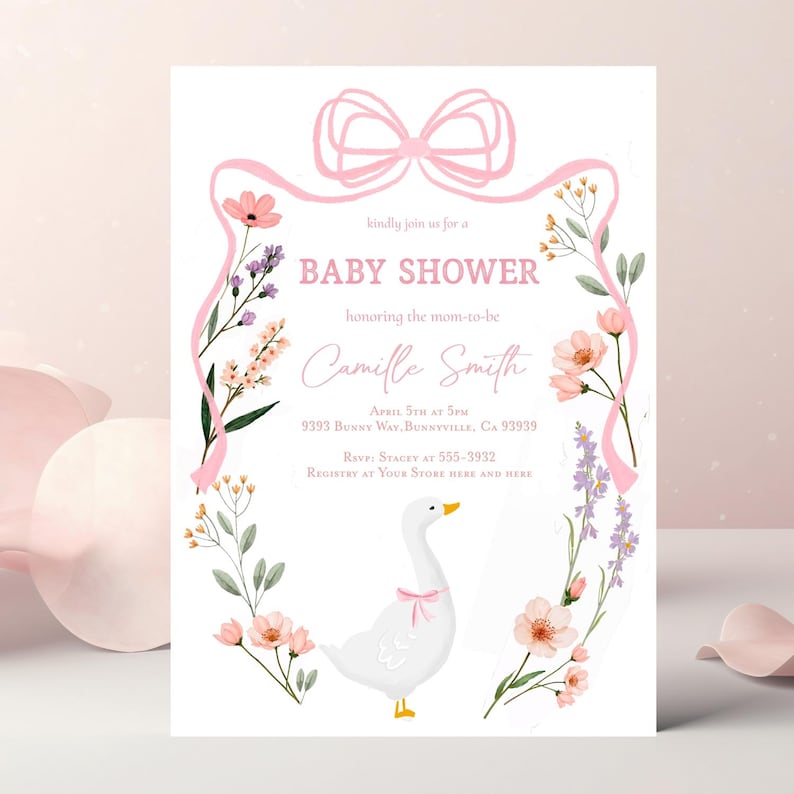May include: A pink and white baby shower invitation featuring a floral wreath and a white goose with a pink bow. The invitation reads "kindly join us for a baby shower honouring the mom-to-be Camille Smith April 5th at 5pm 9393 Bunny Way, Bunnyville, CA 93939 RSVP Stacey at 555-3932 Registry at Your Store Here and Here"