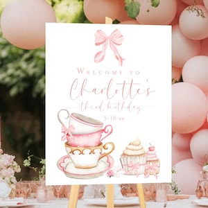 May include: A pink and white welcome sign for a birthday party. The sign features a stack of teacups, a cupcake with a pink bow, and the text "Welcome to Charlotte's third birthday 5-10-xx".