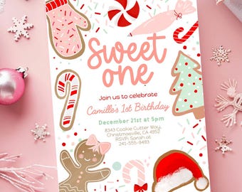 May include: A festive invitation with a pink background and holiday-themed illustrations. The text reads "Sweet One" and invites guests to Camille's 1st birthday on December 21st. Gingerbread people, candy canes, and a Santa hat are featured.