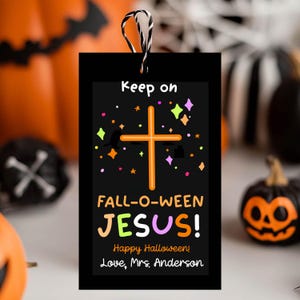 May include: A rectangular black gift tag with a black and white string loop. The tag features an orange cross, colorful star icons, and the text: Keep on FALL-O-WEEN JESUS! Happy Halloween! Love, Mrs. Anderson in orange, yellow, and purple.