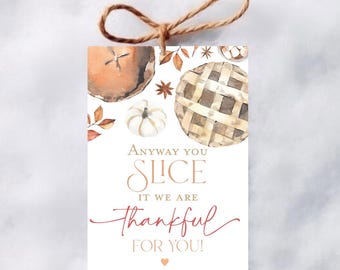 May include: A rectangular paper gift tag with a brown twine loop at the top. The design features watercolor illustrations of pies, a pumpkin, and leaves. The text reads: ANYWAY YOU SLICE IT WE ARE THANKFUL FOR YOU! followed by the name Olivia Anthony.